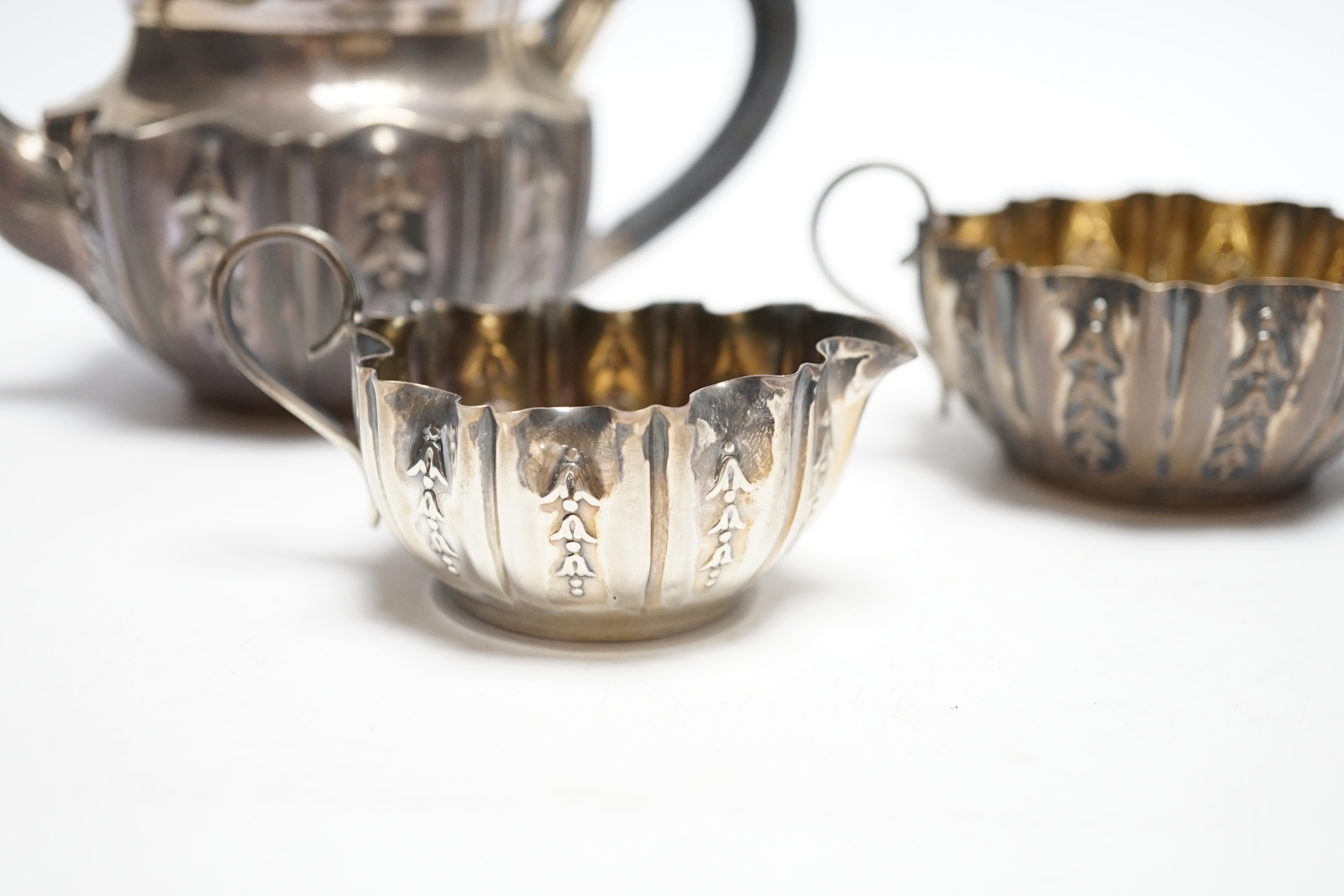 A late Victorian bachelor's repousse silver three piece tea set, Sheffield, 1894/5, gross 11.3oz.